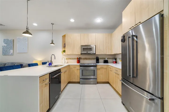 The well-appointed kitchen offers STAINLESS STEEL APPLIANCES, ample storage, a waterfall counter with casual bar seating, pendant lighting, and recessed lighting that adds a modern feel to the space.