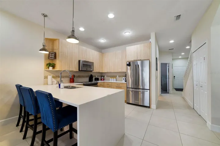 The well-appointed kitchen offers STAINLESS STEEL APPLIANCES, ample storage, a waterfall counter with casual bar seating, pendant lighting, and recessed lighting that adds a modern feel to the space.