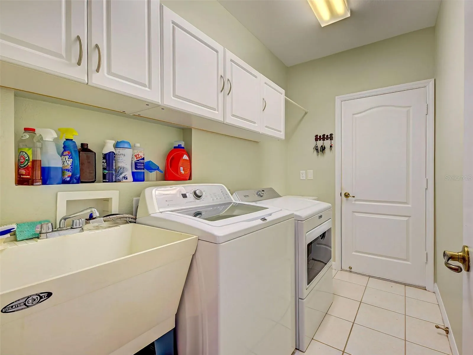 The laundry room is complete with a laundry tub and built in cabinets. There is a door into the garage.
