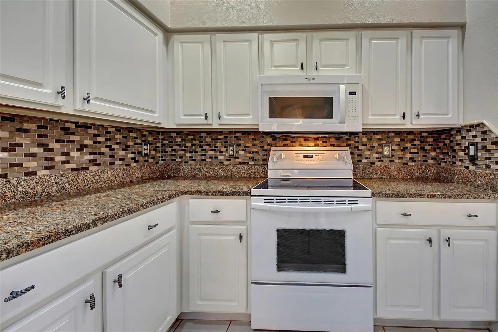 The beautiful kitchen cabinets are only four years old, and complimented by granite counters and tiled backsplash.