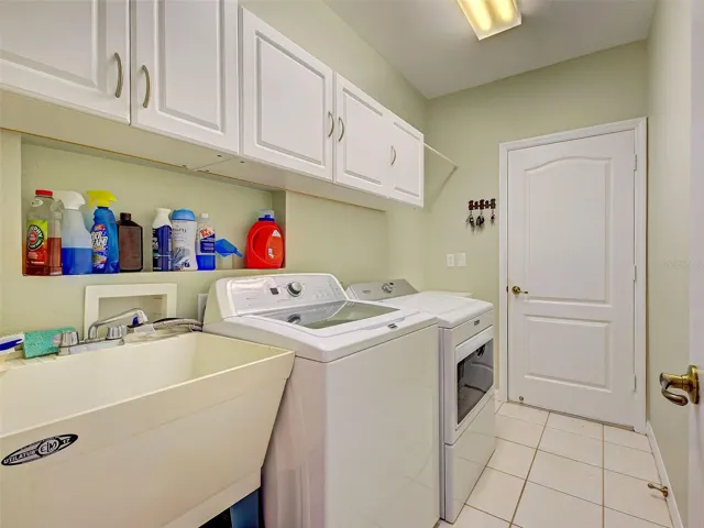 The laundry room is complete with a laundry tub and built in cabinets. There is a door into the garage.
