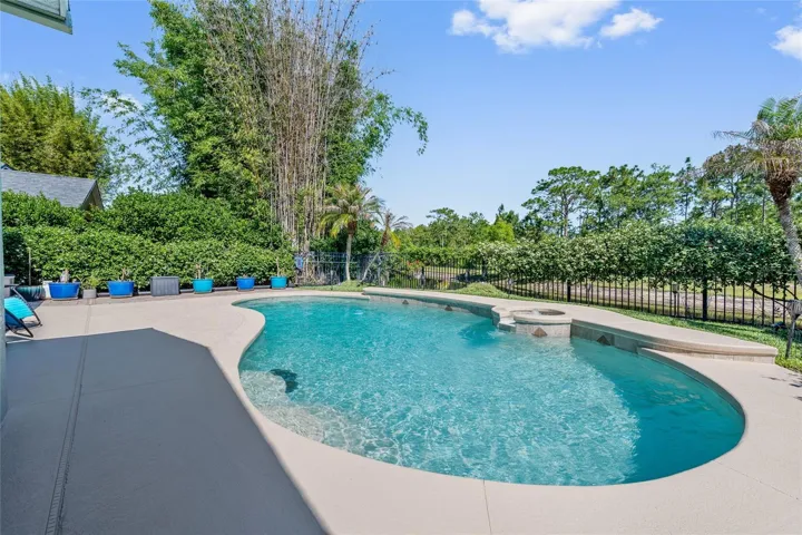 open pool and large pool deck with jasmine on fence surrounding pool