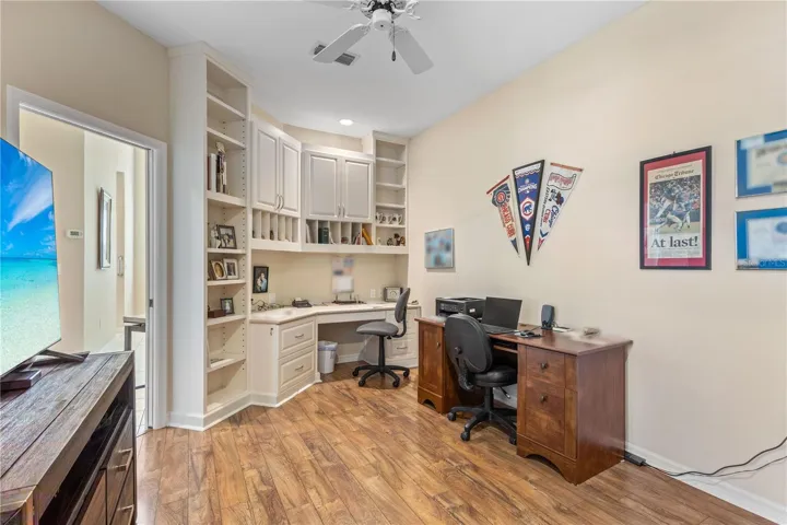 Flexible office or den space featuring custom built-in cabintery, generous storage, and rich wood flooring - ideal for working from home