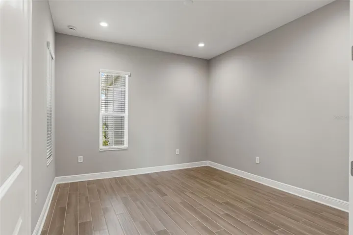 Versatile flex room with natural light and wood-look tile flooring, ideal for a home office, den, or hobby room.