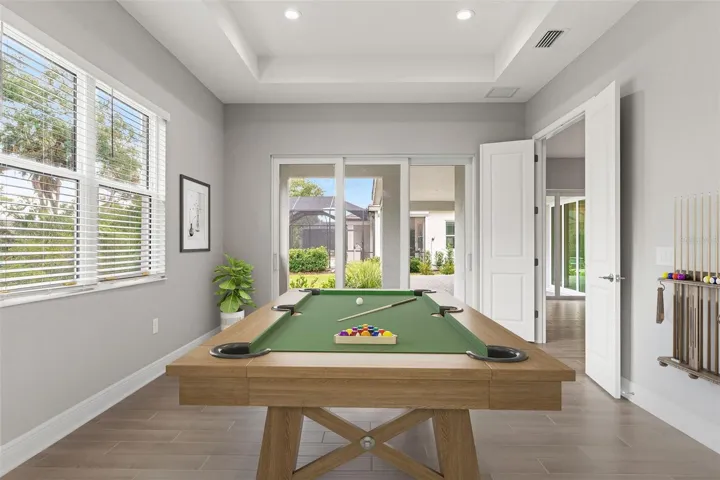 Flex/Game Room – Versatile flex space with room for a billiards table, media lounge, or hobby area, enhanced by large sliding glass doors overlooking the outdoor living space.