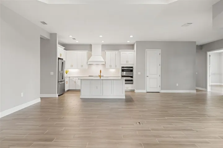 Spacious main living area centered around a designer kitchen with a large island, quartz countertops, custom cabinetry, and stainless steel appliances.