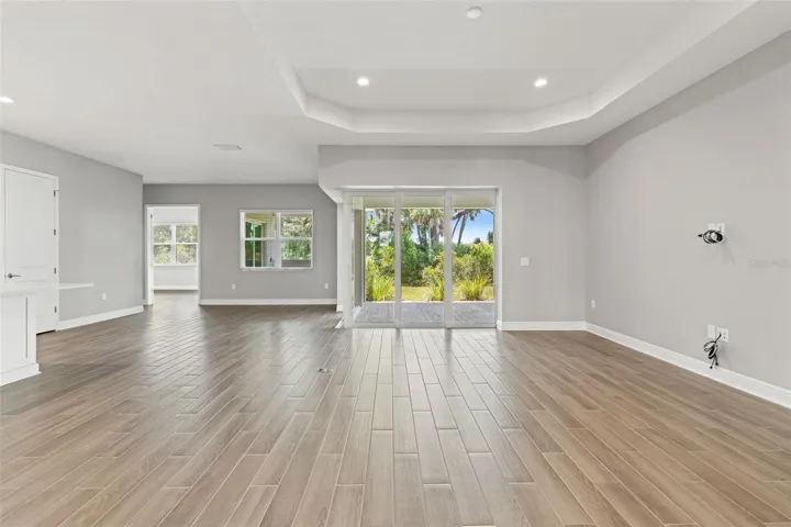 Spacious living area with tray ceilings and sliding glass doors opening to the covered lanai and private backyard views.