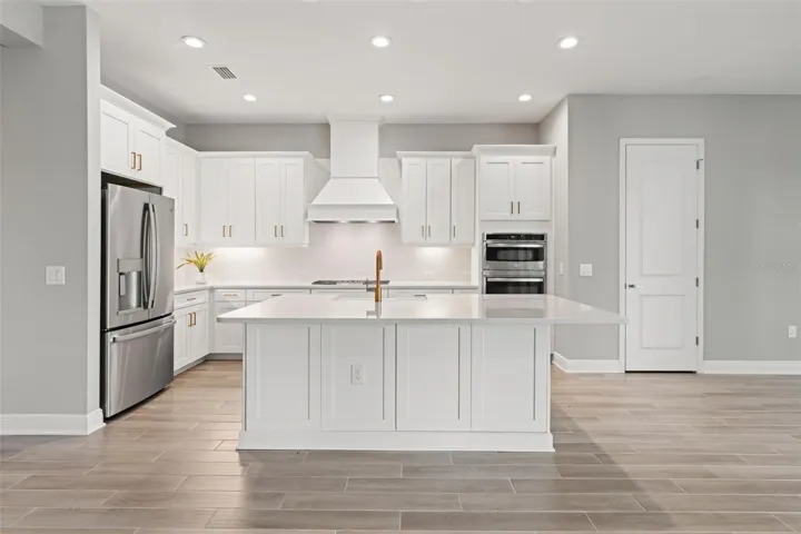 Stylish gourmet kitchen featuring quartz countertops, shaker-style cabinetry, stainless steel appliances, double wall ovens, and a large center island with seating.