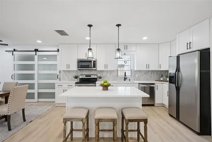 The sleek modern kitchen delivers desirable shaker style cabinetry, complimentary countertops and backsplash, stainless steel appliances, pendant lighting and the large island has casual bar seating.