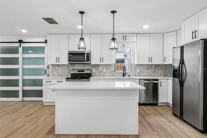 The sleek modern kitchen delivers desirable shaker style cabinetry, complimentary countertops and backsplash, stainless steel appliances, pendant lighting and the large island has casual bar seating.