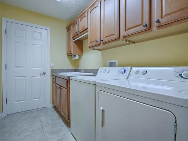 LAUNDRY ROOM OFF THE KITCHEN; WASHER AND DRYER CONVEY WITH THE HOME. EXTRA CABINETS FOR MORE STORAGE AND A LARGE SOAKING TUB. DOOR LEADS TO THE GARAGE.