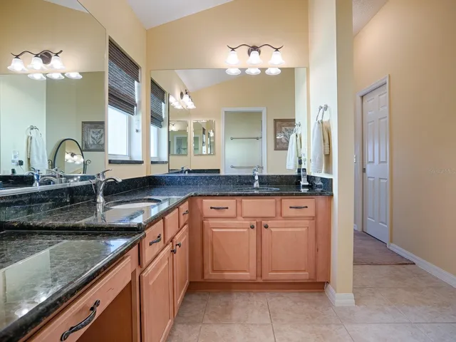 PRIMARY BATHROOM WITH TILE FLOORING, BEAUTIFUL GRANITE COUNTER TOPS, DUAL SINKS, VANITY AREA, LARGE LINEN CLOSET AND WINDOW FOR NATURAL LIGHT.