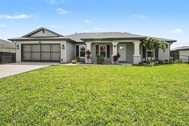 Single-story residence featuring a gray exterior stucco finish, a two-car garage with a screen door, and a covered entryway supported by two columns
