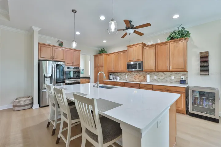 Large breakfast bar compliments the kitchen and modern touches like newer appliances, double stack wall ovens, cooktop, recessed lights and mosaic backsplash.