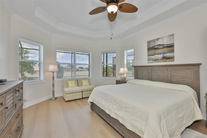 Primary Bedroom is oversized, with trey ceilings, modern flooring and large windows for natural sunshine and overlooking the patio and pool.