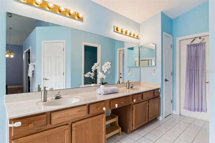 This spacious owner's bathroom features a private water closet, extended vanity space, and convenient direct access out to the screened patio.