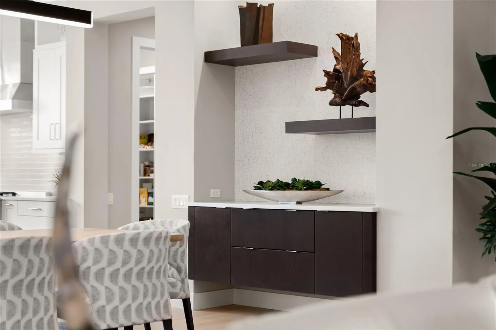 The dining room has a custom built-in buffet cabinetry with shelving, wallpaper accents, and recessed lighting.