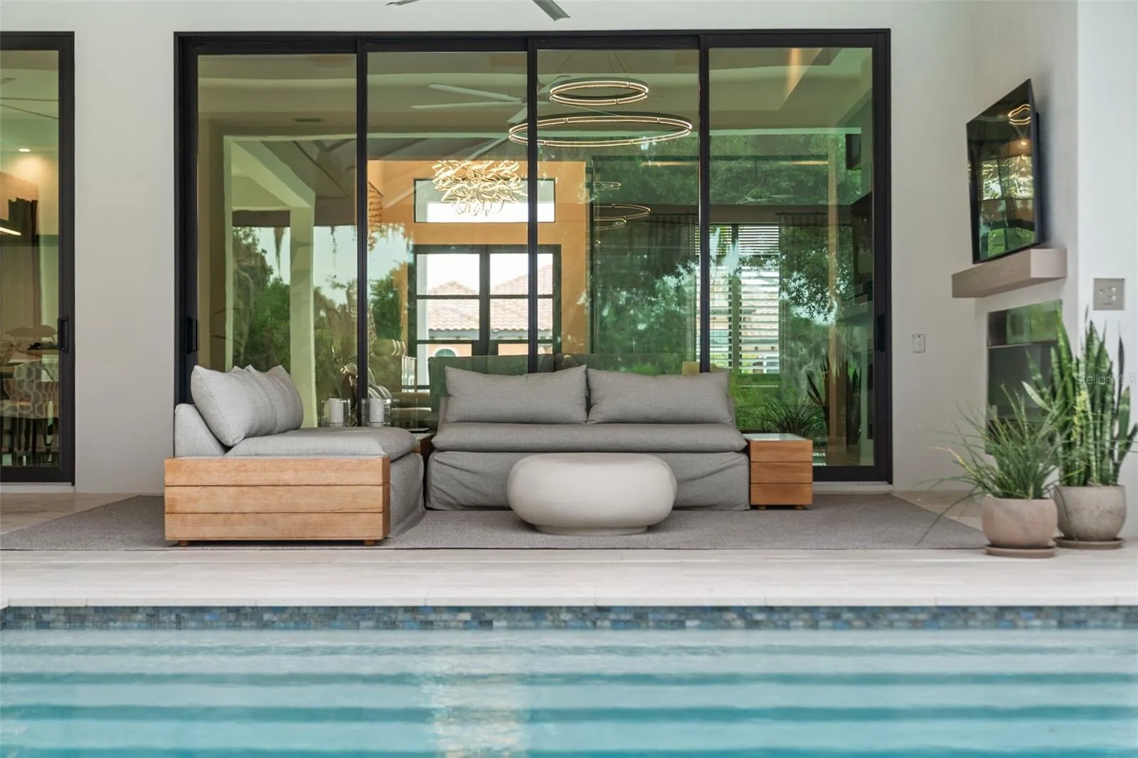 TThe expansive outdoor living area features a cozy fireplace, mounted television, and oversized lounge seating.
