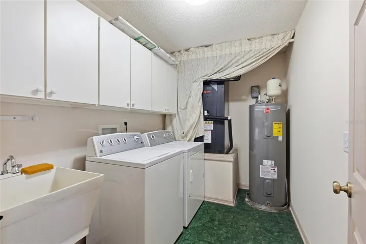 Utility room with washer, dryer, laundry sink, HVAC and water heater.