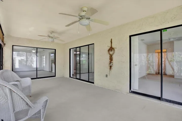 Another view of the massive screened lanai showcasing the multiple sets of sliding glass doors that seamlessly connect the indoor and outdoor living spaces.
