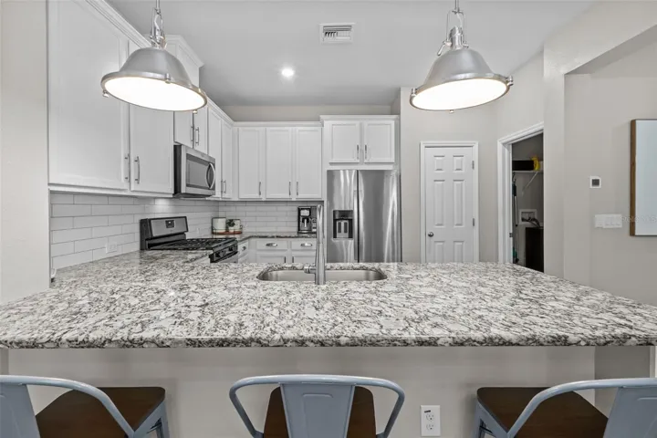 Beautiful kitchen features white cabinetry, granite countertops, and stainless steel appliances