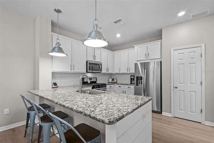 Beautiful kitchen features white cabinetry, granite countertops, and stainless steel appliances