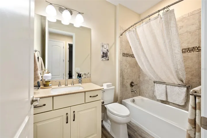 Third bathroom featuring a tub with tiled shower walls.