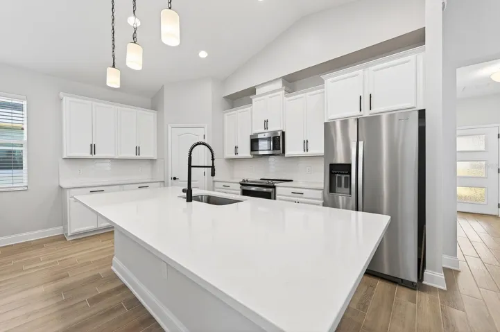 Features include UPGRADED STAINLESS STEEL APPLIANCES, a tiled backsplash, upgraded fixtures and hardware, pantry storage, generous cabinet and counter space, and a large center ISLAND with bar seating highlighted by stylish pendant lighting.