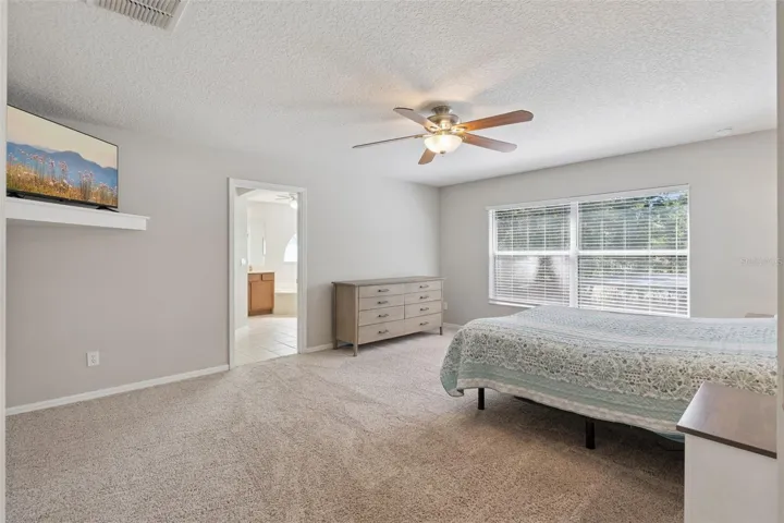 Large windows bring natural light into the primary suite throughout the day.