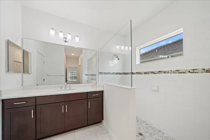 PRIMARY BATHROOM with two walkin closets, single sink, walk in glass shower and separate commode