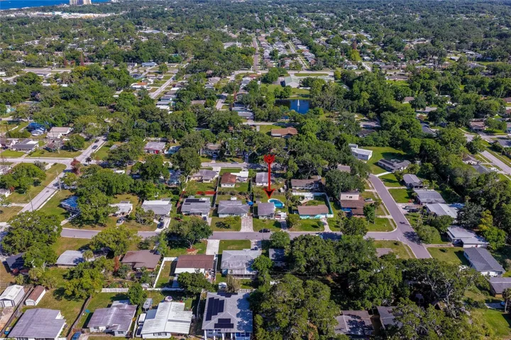High-altitude aerial view marked with a red arrow, illustrating the property's central location within a lush, tree-lined residential community.
