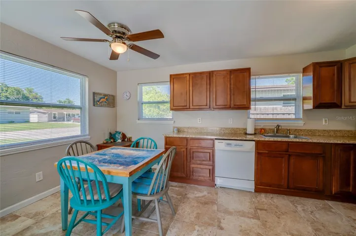 Charming dining niche featuring a vibrant blue table setup tucked next to an expansive kitchen counter with warm wood cabinetry.