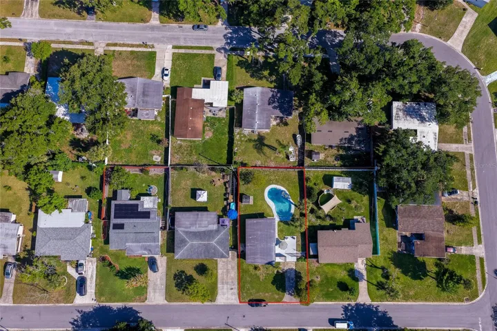 Top-down lot aerial outlined in red, clearly defining the property boundaries, spacious yard layout, and pool placement relative to surrounding neighbors.