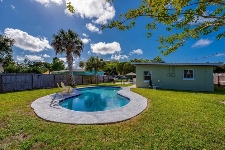 Sun-drenched outdoor oasis featuring mature palm trees and a pristine pool ideal for warm-weather relaxation.