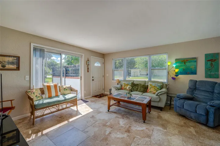 Welcoming entryway and seating area showcasing large windows that flood the tiled living room with abundant natural light.