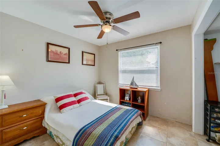 Cozy bedroom featuring a ceiling fan, a large window, and a spacious closet alcove.