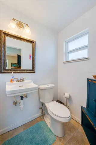 Functional half-bathroom equipped with a classic wall-mounted sink, a decorative framed mirror, and a frosted privacy window.