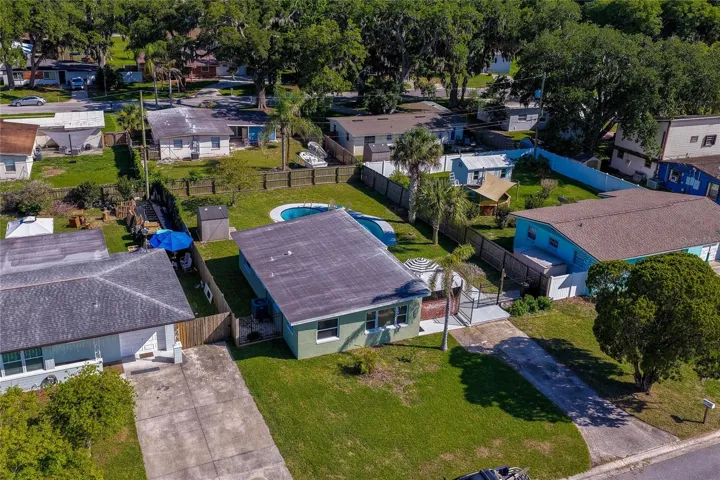 Elevated aerial view showcasing the home’s layout within the neighborhood, highlighting the expansive backyard complete with an in-ground swimming pool.