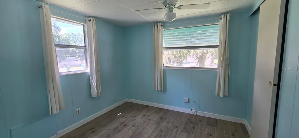 Bedroom 2 — Corner WindowsSecond bedroom with two windows, palm tree views, new LVP flooring, ceiling fan, and a sliding closet door — bright and ready to go.