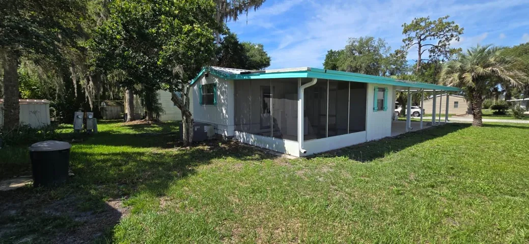 Back/Side Exterior — Screened Porch + CarportScreened porch for bug-free Florida mornings, covered carport for your vehicle, and a big open yard framed by mature trees — this lot lives large.