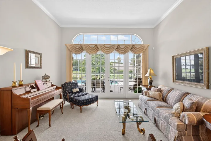 Living room overlooks the screened pool and lanai via beautiful wall of French doors.