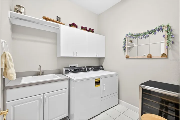 Laundry room with large laundry tub and storage cabinets is just off the back hall leading to the three car garage.