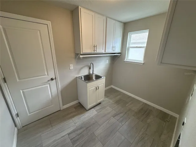 laundry room with utility sink and storage cabinets