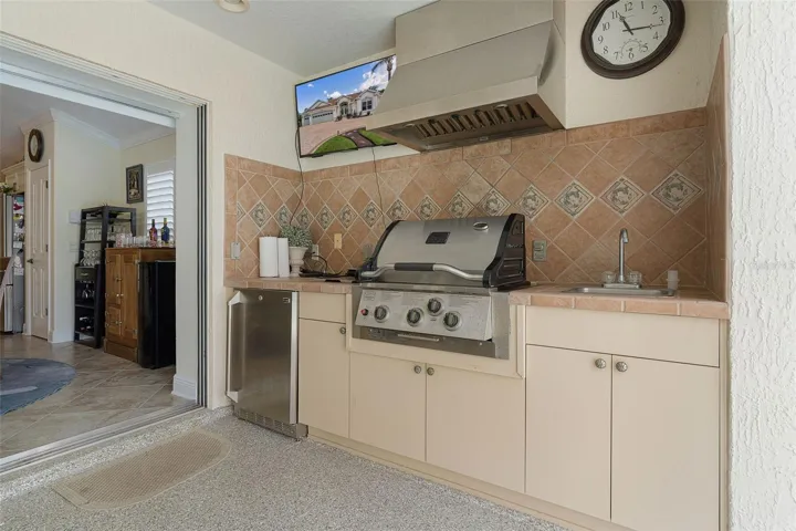 Outdoor kitchen with grill, refrigerator & sink with a beautiful tile countertop