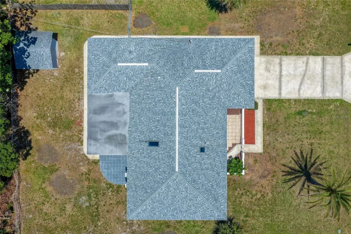 A crisp bird's-eye view detailing the property's layout, roof structure, and back patio area. The expansive yard features a standalone storage shed and plenty of open green space.