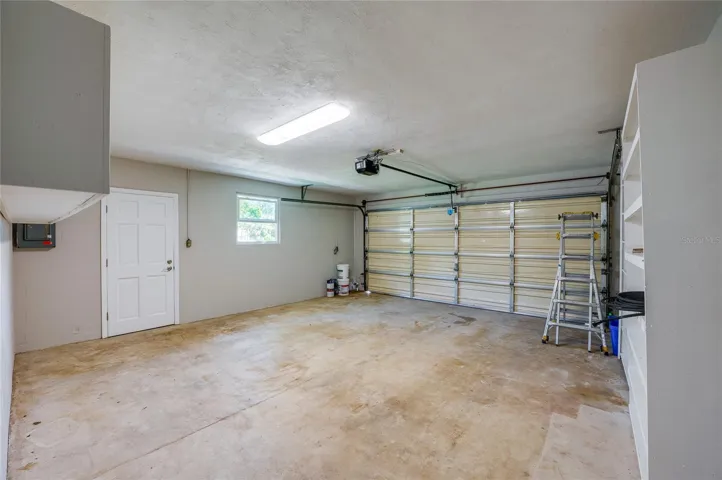 Generous two-car garage with built-in shelving units, and access to the main house. The wide layout provides plenty of extra room for vehicle parking, a workshop, or additional storage.