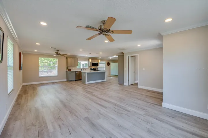 Bright and airy open-concept living space featuring vinyl flooring, recessed lighting, and a view into the kitchen. The expansive layout provides plenty of versatility for both relaxing and entertaining.