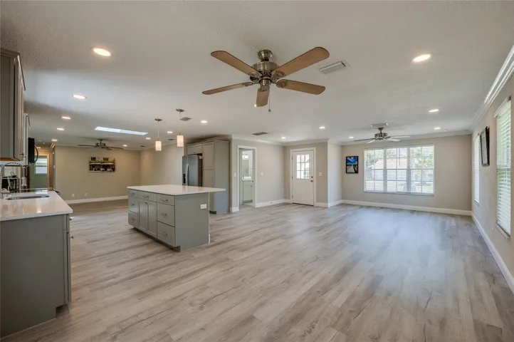 Multi-functional living zone seamlessly connected to the heart of the home, showcasing an expansive breakfast island with sleek pendant lighting. The seamless floor plan creates a perfect flow for everyday living.