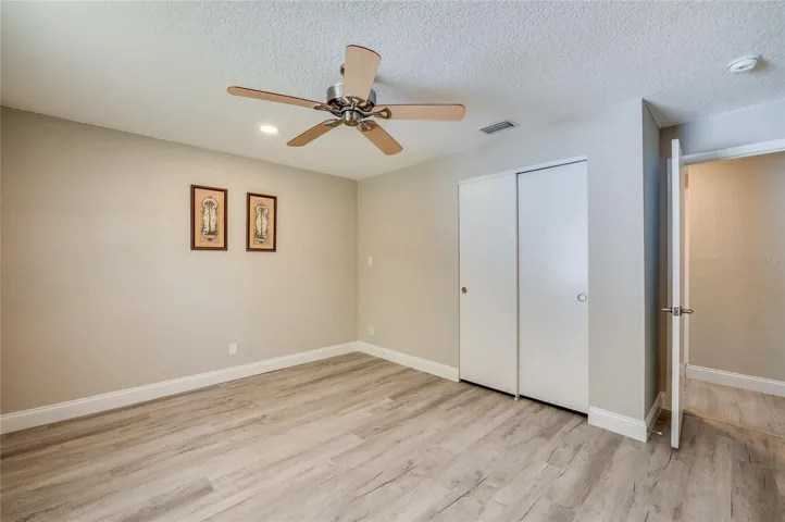 Alternate view of the bedroom highlighting a sizeable sliding-door closet, vinyl flooring, and neutral wall tones perfect for any decor.