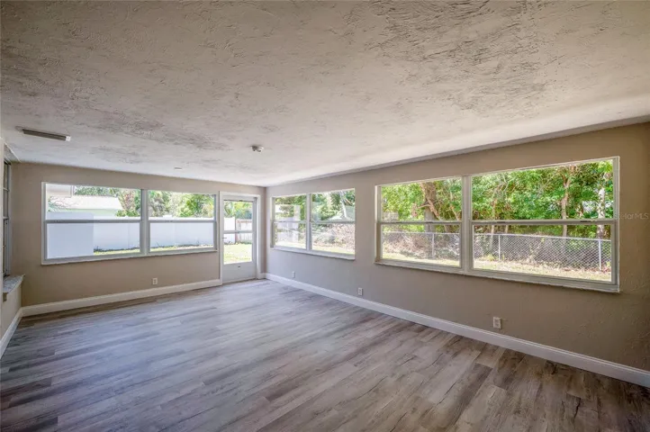 Sunroom lined with wrap-around windows that offer peaceful views of the surrounding greenery and backyard.